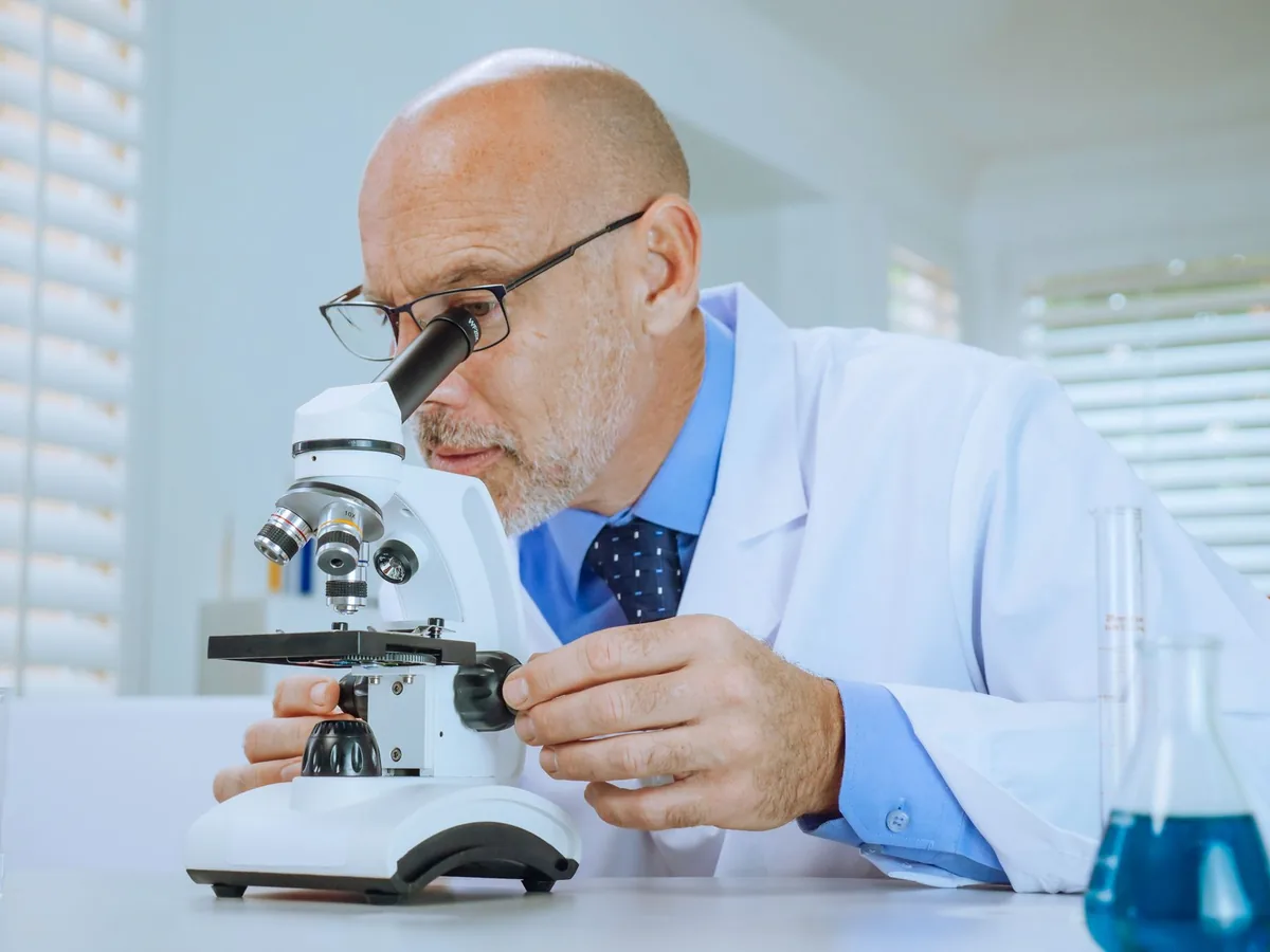 muž v laboratoři se dívá do mikroskopu
