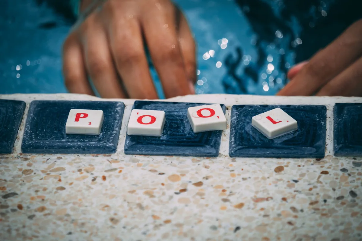 ruka u bazénu s dlaždicemi s nápisem pool