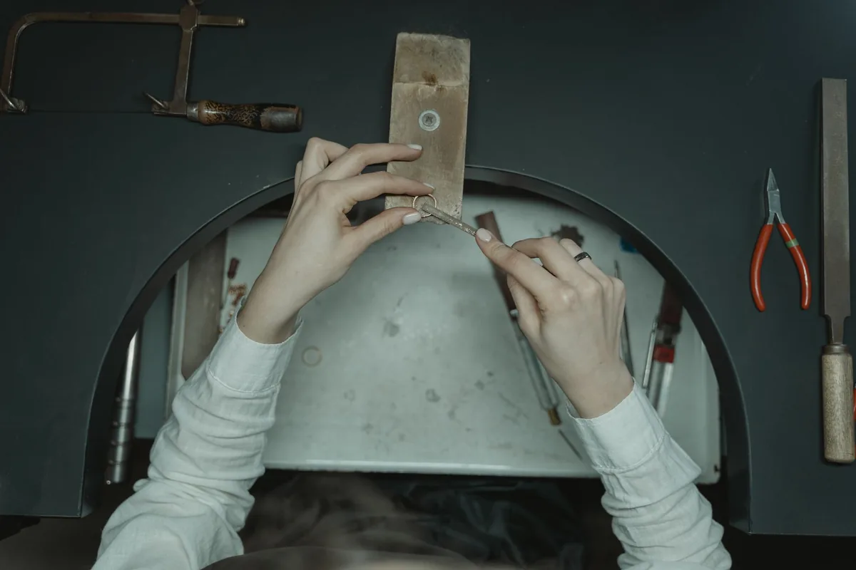 ruce pilují šperk na zlatnickém kolíčku